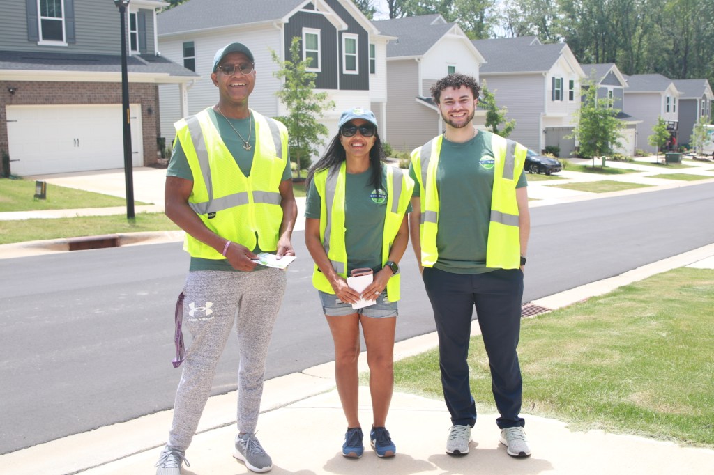 Three people stand for a photo wearing high-visibility vests.